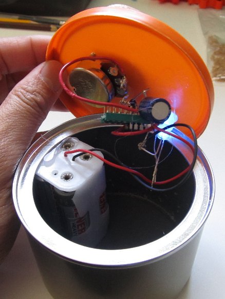 Previous image but the can's cover is raised slightly revealing circuitry and battery