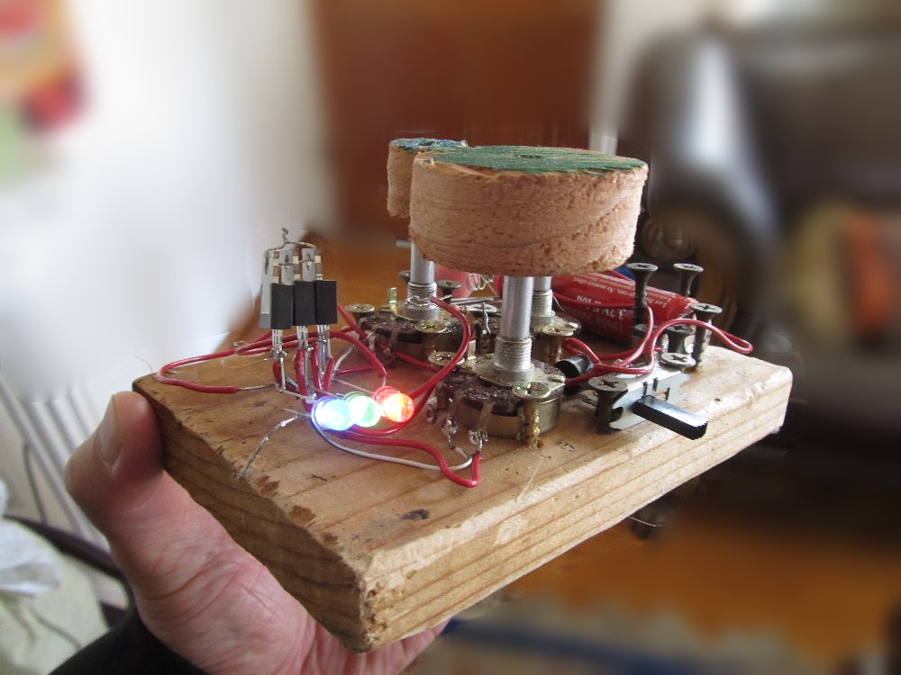 A wood board with two controllers, a circuit, and three lights on it
